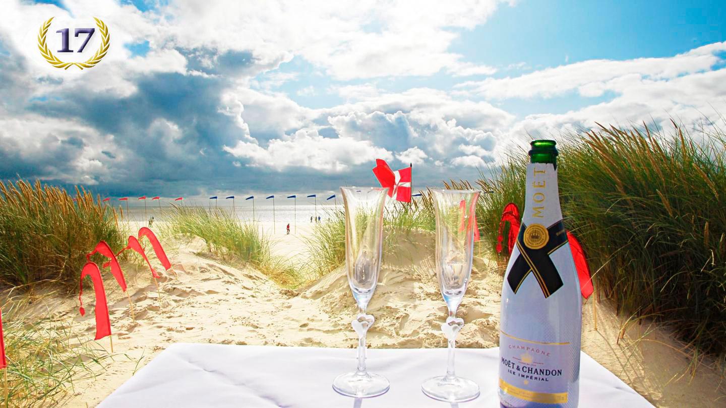 Hochzeitspaar am Strand mit Sektgläsern und funkelnden Eheringen